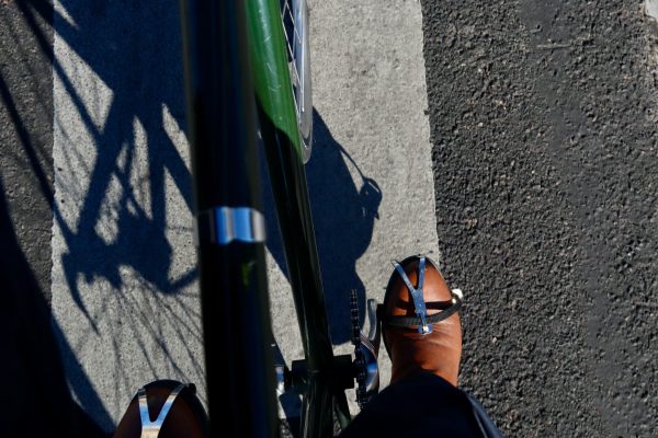 Pohled ze sedla jízdního kola na nohy v pánských společenských botách